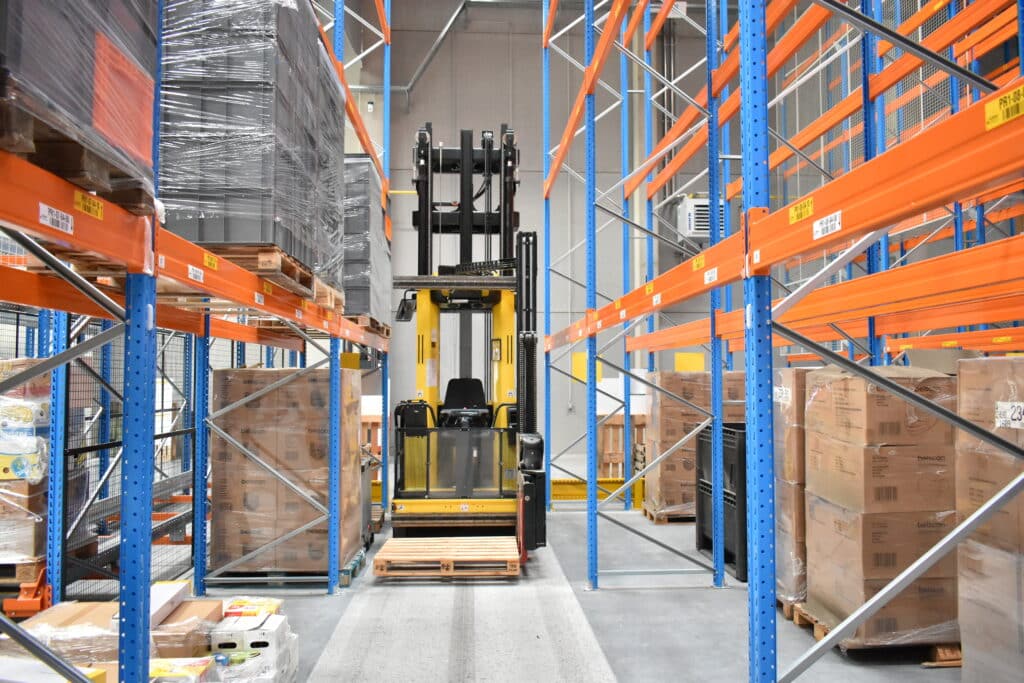 Heftruck in smal 2 meter breed gangpad tussen hoge palletrekken tot 10,2 meter in logistiek testcentrum Fabriek Logistiek