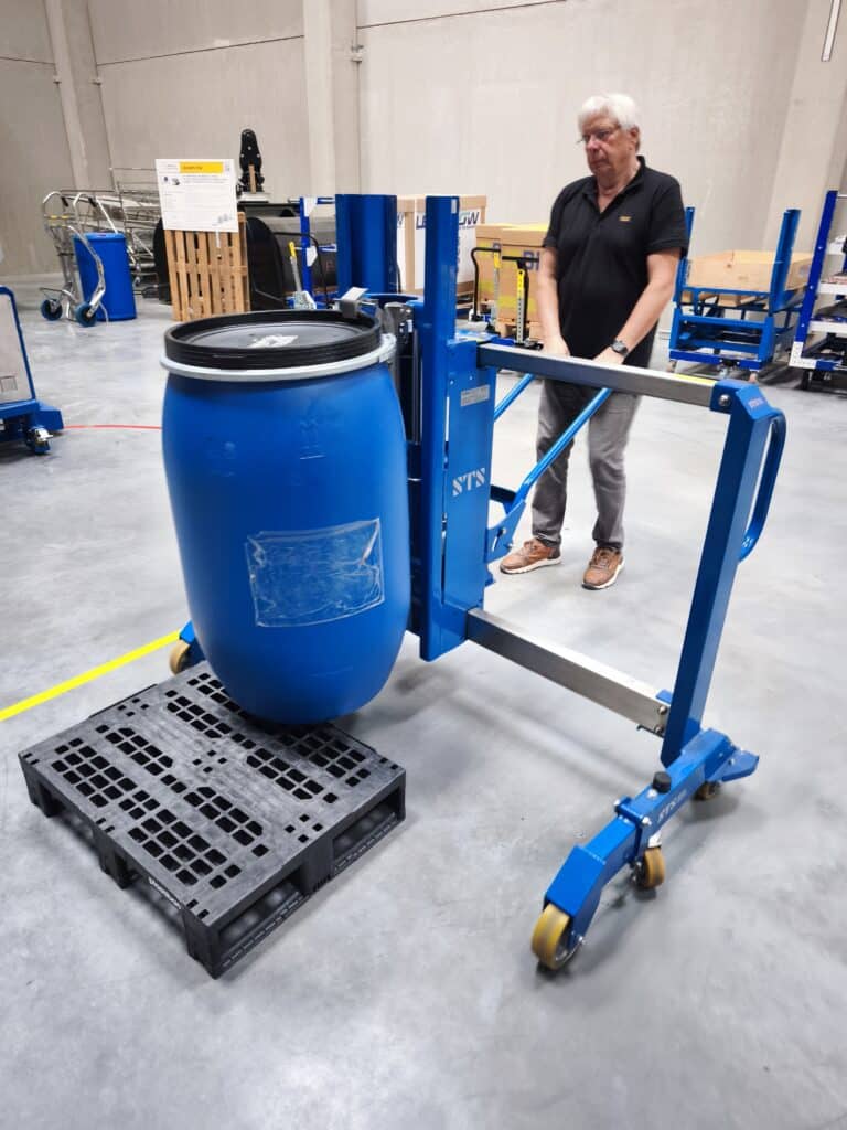Medewerker test een blauwe vatenpicker van NTS die een vat op een kunststof pallet plaatst